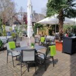 Terrasse mit Decken an Stühlen und Palme